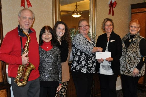 Musicians and organization representatives pose for photo with a check