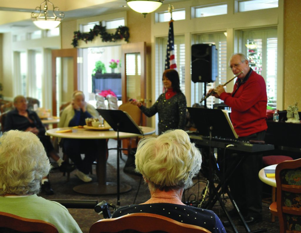 A man and woman perform music for senior adults.