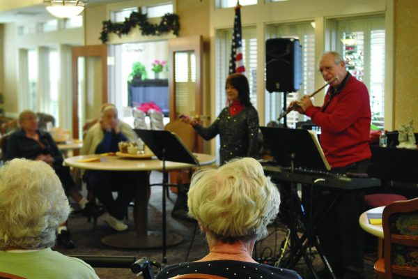 A man and woman perform music for senior adults.