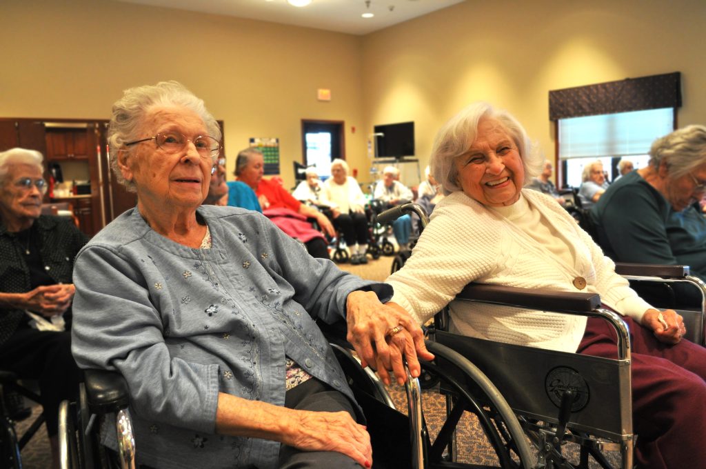 Two women in wheelchairs smile at a performance
