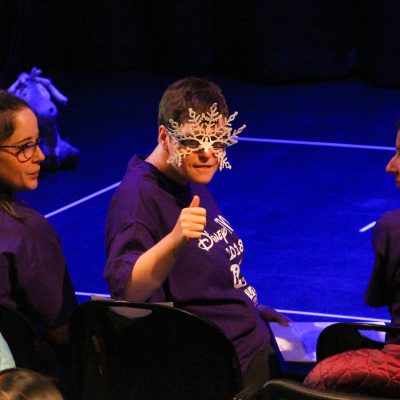 Student performer wearing a mask gives a thumbs-up