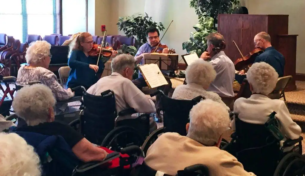 Nursing home residents gather for a small ensemble string performance.