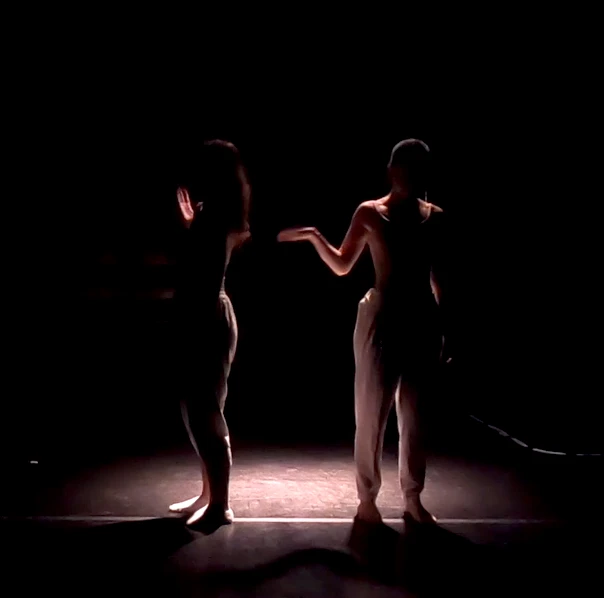 Two silhoutted dancers onstage
