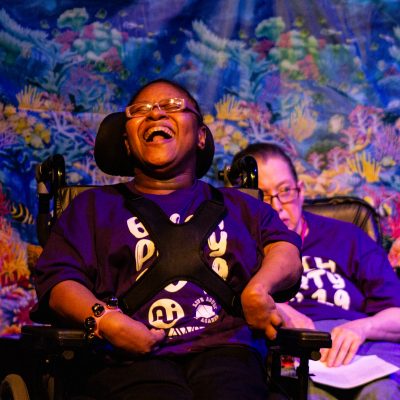 student performer in a wheelchair sings with a smile
